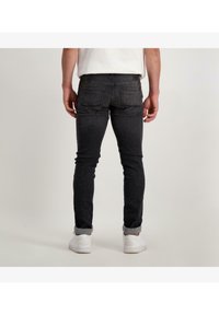 Zwarte slim-fit jeans met een gladde denimtextuur, met twee achterzakken en een opgerolde boord bij de enkels.