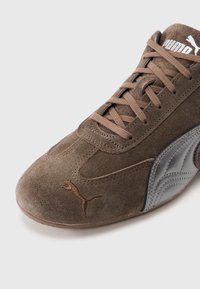 Adidași din piele întoarsă maro închis cu un design elegant, având un panou lateral argintiu și un logo brodat maro. Înșirați cu șireturi maro asortate.