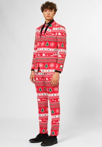 Completo natalizio rosso con motivi di alberi, fiocchi di neve e renne. Camicia nera sotto e scarpe. Vestibilità su misura.