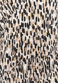 Tkanina s vzorem obsahuje nepravidelné černé, béžové a krémové tvary. Měkká textura s mírně nařaseným designem vytváří vizuální zajímavost.