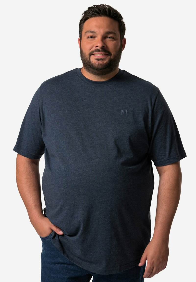 Męska granatowa koszulka z okrągłym dekoltem, wykonana z miękkiego materiału, z krótkimi rękawami i małym logo na piersi, zestawiona z ciemnymi dżinsami.