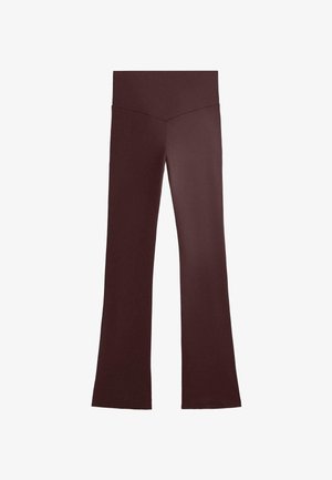 Burgundy vida byxor i ett mjukt, stretchigt material. Har en hög midja och en figurnära silhuett runt höfterna som avsmalnar nedtill.