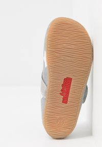 Pohja harmaasta lasten kengästä, jossa on teksturoitu kumipohja, koko 25, ja punainen "Living Kitzbühel" -brändäys pohjassa.