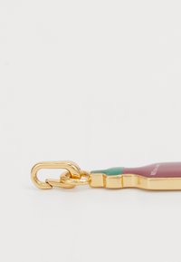 Porte-clés en métal doré en forme de bouteille avec un design rouge et vert. Texture lisse avec une finition brillante. Idéal pour un usage quotidien.