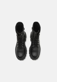 Black lace-up boots with a rounded toe, padded collar, and decorative stitching. Features a side zipper and textured rubber sole.
