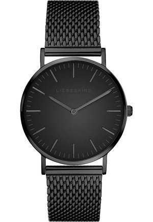 Montre noire ronde avec une finition mate, un design minimaliste, de fins index horaires et un bracelet en métal maillé noir. Équipée d'une couronne sur le côté.