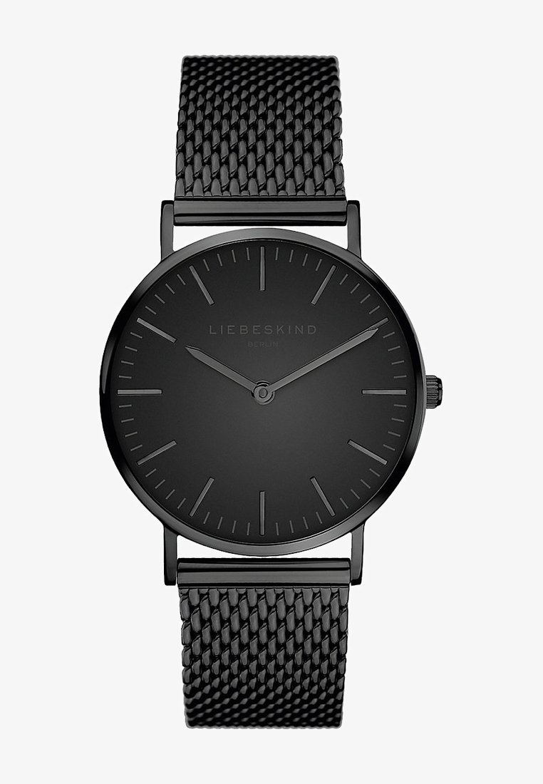 Rund svart klocka med en matta yta, minimalistisk design, tunna timmarkörer och ett svart nätmetallarmband. Har en krona på sidan.