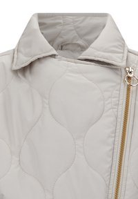 Gepolsterte hellgraue Jacke mit Kragen, goldenen Reißverschlussdetails und weicher Textur mit Wellenmustern.