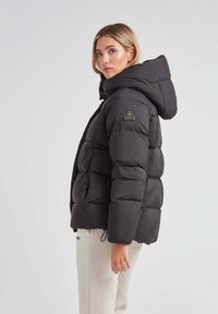 Czarna kurtka puchowa z kapturem, pikowany design, elastyczne mankiety i naszywka z logo na ramieniu. Miękka tekstura i ocieplenie z wypełnieniem.