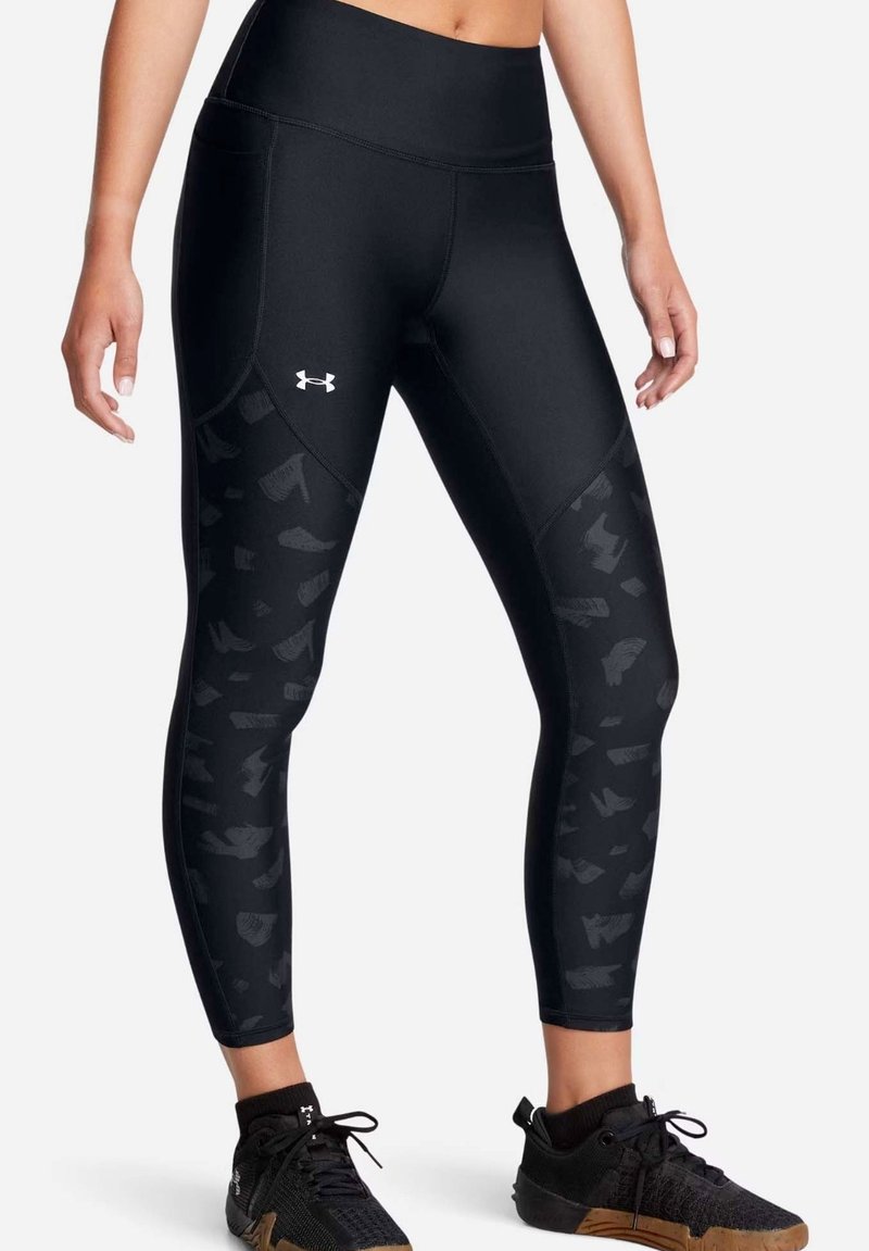 Leggings deportivos negros con una cinturilla alta, que presentan un patrón texturizado en los lados, elaborados con un material elástico. El logo es visible.