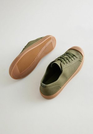 Olivovo zelené plátěné tenisky s okrúhlym prstom, šnúrkami na prednej strane a textúrovanou gumovou podrážkou v hnedej farbe. Obsahujú švy a polstrovaný golier.
