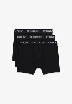 Trois caleçons boxer noirs empilés, chacun avec une ceinture noire portant la marque "GUESS JEANS" en blanc.