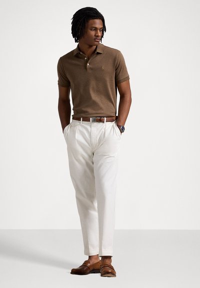 Camisola polo castanha de mangas curtas, calças bege e mocassins castanhos. Características notáveis: tecido texturizado e logótipo subtil.