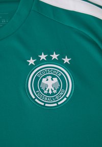 Camisa de futebol verde-escura com o logótipo da Deutscher Fussball-Bund, apresentando uma águia branca e quatro estrelas brancas acima dela.