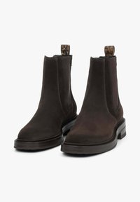 Ciemnobrązowe zamszowe botki do kostki z elastycznymi panelami bocznymi i uchwytem w panterkę. Posiadają grubą gumową podeszwę dla lepszej stabilności.