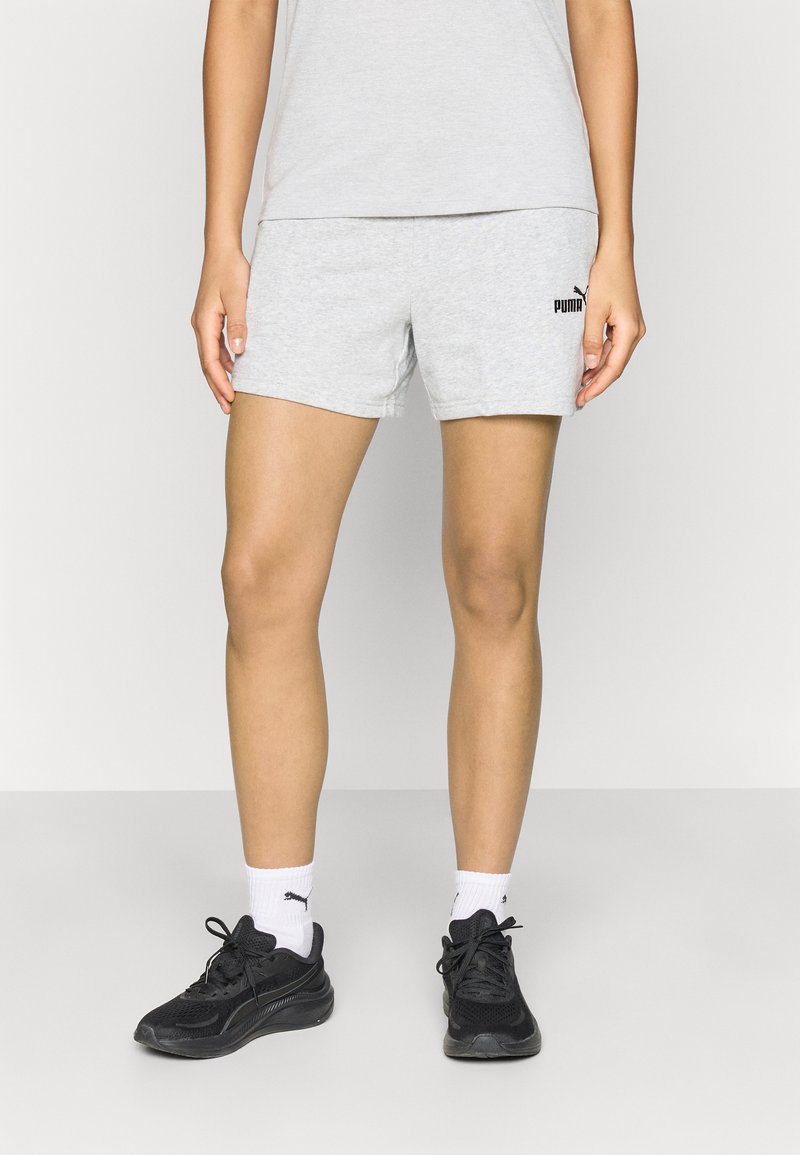 Γκρι βαμβακερά σορτς με ελαστική μέση και μαύρο λογότυπο Puma, συνδυασμένα με μαύρα αθλητικά παπούτσια και λευκές κάλτσες. Απλό σχέδιο, εφαρμοστή γραμμή.