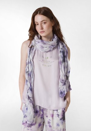 Purple floral-patterned scarf draped over a light lavender top. Blend of soft, flowing fabrics; loose fit. Accents of green text embellishment.