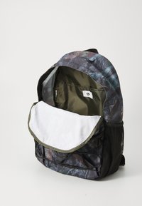 Rugzak met een camouflagedessin in verschillende tinten, voorzien van een opvouwbare klep, gaas zijvakken en een intern merklabel.