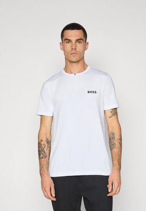 Weißes T-Shirt mit Rundhalskragen, das ein kleines schwarzes "BOSS"-Logo auf der Brust trägt, aus glattem Stoff gefertigt und mit kurzen Ärmeln. Kombiniert mit dunklen Hosen.