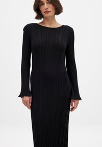 Melnas ribotas garām piedurknēm kleita ar apaļu kakla izgriezumu un izplestu, krokotu piedurkņu galotnēm. Izgatavota no tekstūrēta auduma, pieguļoša silueta.