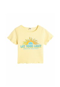 Gul cropped t-shirt med korte ærmer, ribbet tekstur, med et solgrafik og teksten "LAD DIN LYS STRÅLE KLART" i blå.