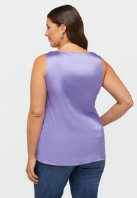 Bezramienny fioletowy top z satyny o gładkiej teksturze i okrągłym dekolcie, z luźnym krojem i lekko zaokrąglonym dołem.
