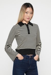 Gestreifter Polo-Pullover in Creme und Schwarz, mit Kragen, Knopfleiste und geripptem Saum. Lange Ärmel mit ausladenden Manschetten.
