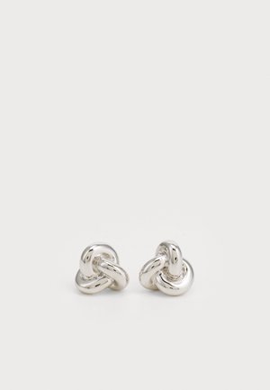 Silver knot-shaped earrings with a polished finish, featuring intertwined design and smooth texture. Small, rounded shape enhances detail.