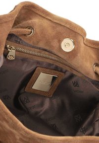 Intérieur d'un sac seau en daim marron avec une doublure en tissu de marque, une poche zippée avec une fermeture éclair dorée et une fermeture magnétique à pression en haut.