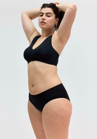 Svart bikini-set med en v-ringad bralette med breda axelband och matchande låga trosor, tillverkad av smidigt, elastiskt material.