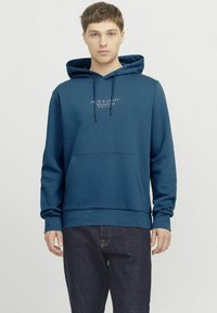 Felpa blu navy realizzata in un tessuto morbido. Presenta una tasca frontale, cappuccio regolabile con cordino e una stampa del logo sul petto. Vestibilità classica.