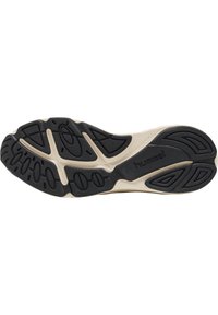 Suela de zapato con un patrón de tracción de goma negra sobre una entresuela beige. Presenta curvas y ranuras para el agarre; texto "hummel" en relieve.