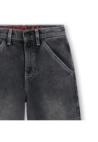 Μαύρο τζιν τύπου denim με ξεθωριασμένη υφή, λευκά ραφές, κλείσιμο με κουμπί και λοξές τσέπες στο εμπρός μέρος. Κόκκινο λογότυπο στη ζώνη μέσης.