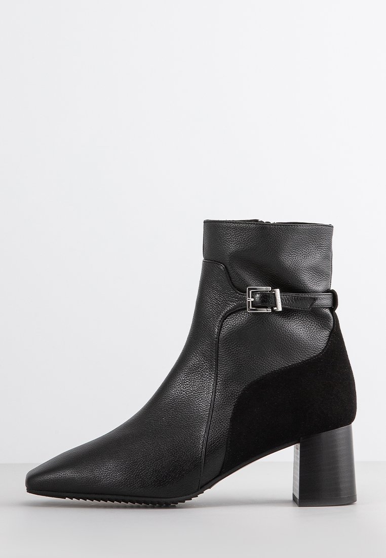 Zwarte enkelboot met een spitse neus, gemaakt van gestructureerd leer met een suede paneel. Heeft een lage blokhak en een gespaccent.