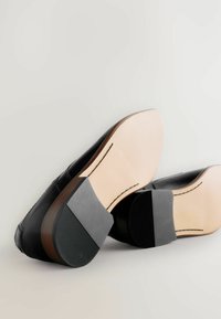 Zwarte leren schoenen met een glad oppervlak, ronde neus en een mix van lichte en donkere rubberen zolen met textuuraccenten.