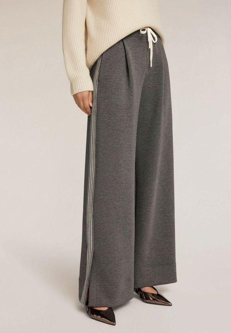 Grijze sweatpants met brede pijpen en zijstrepen, gemaakt van zacht materiaal. Voorzien van een taille met trekkoord en zijzakken.