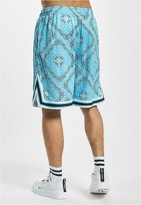 Blue patterned shorts feature a diamond design, elastic waistband, and side slits. Accented with contrasting black and white trim.