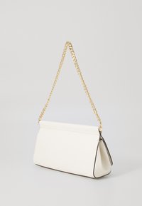 Pochette en cuir blanc avec une chaîne dorée, forme angulaire, bord noir contrastant et une finition lisse.