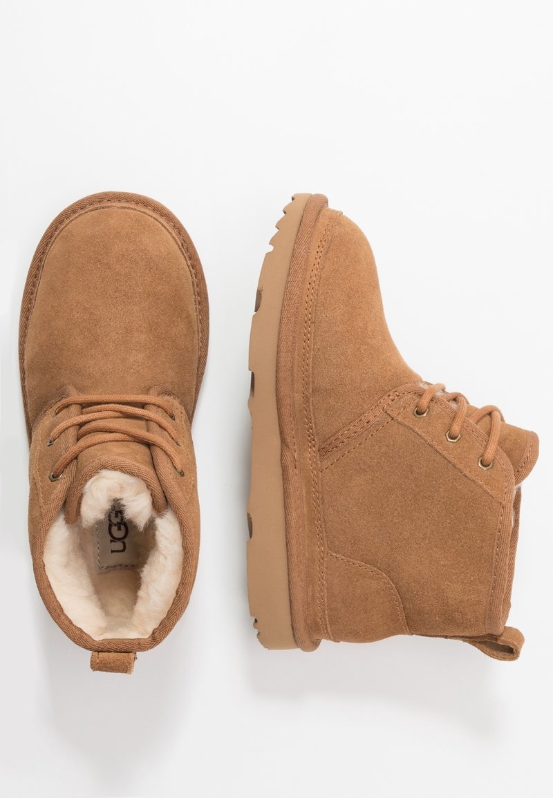 Bottines en daim marron avec semelles en caoutchouc couleur tabac, lacets sur le devant et doublure en peluche blanche, vues de dessus et de côté sur fond blanc.