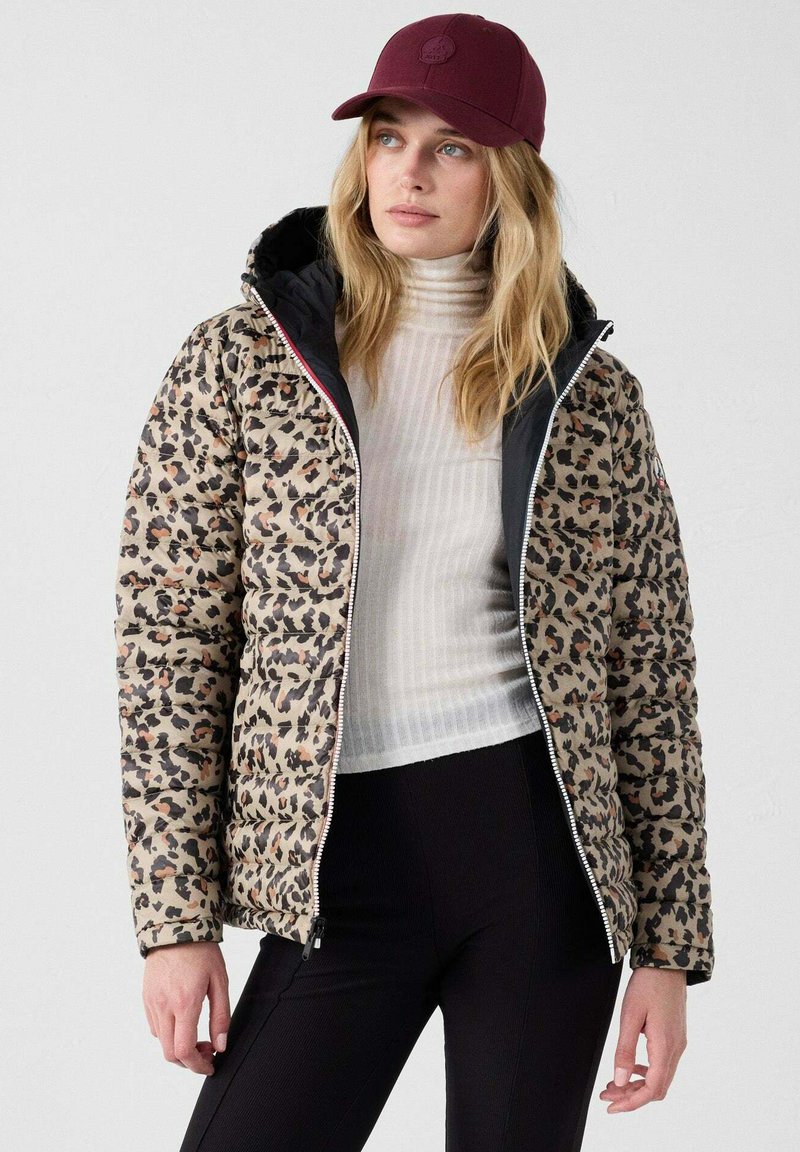 Jasje van pufferstof met luipaardprint en zwarte voering, met ritssluiting en een sportieve pasvorm. Draag het over een witte geribde coltrui en zwarte broek.