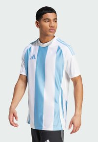 Maillot de sport blanc avec des rayures verticales bleu clair, à manches courtes et col rond ; présente trois rayures bleues sur les épaules et un logo.
