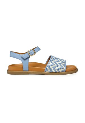 Sandalia azul claro con patrón trenzado en la correa, hebilla ajustable en el tobillo y suela plana beige con poco agarre.