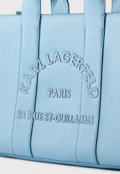 Светлосиня текстурирана кожена чанта с бродиран надпис „KARL LAGERFELD PARIS 21 RUE ST-GUILLAUME“ отпред.