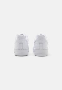 White Nike Air sneakers with a smooth leather upper, textured heel accents, and a low-profile design, featuring a round toe and rubber sole.