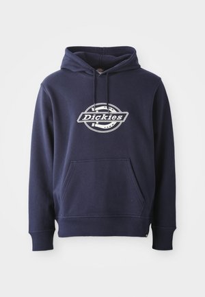 Tengerészkék kapucnis pulóver pamut keverékből készült. Elöl zsebbel és húzózsinórral ellátott kapucnival rendelkezik. Fehér „Dickies” logo látható a mellkasán, kör alakú dizájnnal.