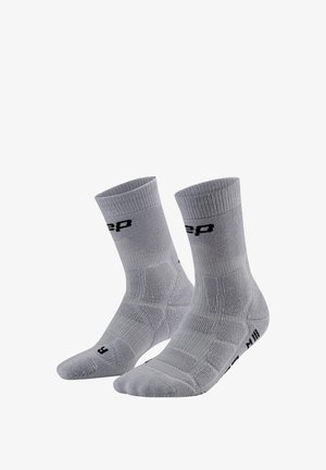 Paar grauer Crew-Socken mit gerippten Bündchen und schwarzer Beschriftung, für linke und rechte Füße entworfen, vor weißem Hintergrund dargestellt.