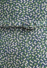 Kudottu kangas, jossa on sinisen, vihreän ja valkoisen geometrinen kuvio. Tekstuuri on pehmeä ja pinnassa on selkeästi kohouma.