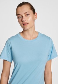 Ljusblå t-shirt tillverkad av mjuk bomull, med klassisk rund hals och korta ärmar, med en slät textur och minimal design.