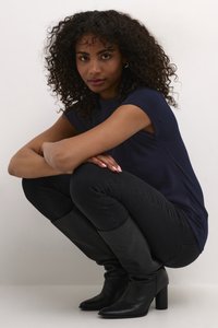 Haut à manches courtes bleu marine associé à un jean skinny noir et des bottes noires à talons hauts, présentant des textures lisses et des coupes ajustées.