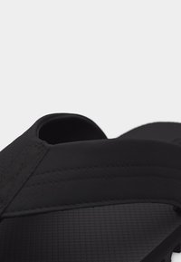 Schwarze Sandale mit strukturiertem Profil und breitem, verstellbarem Riemen über dem Fuß, entworfen für den Freizeitgebrauch.